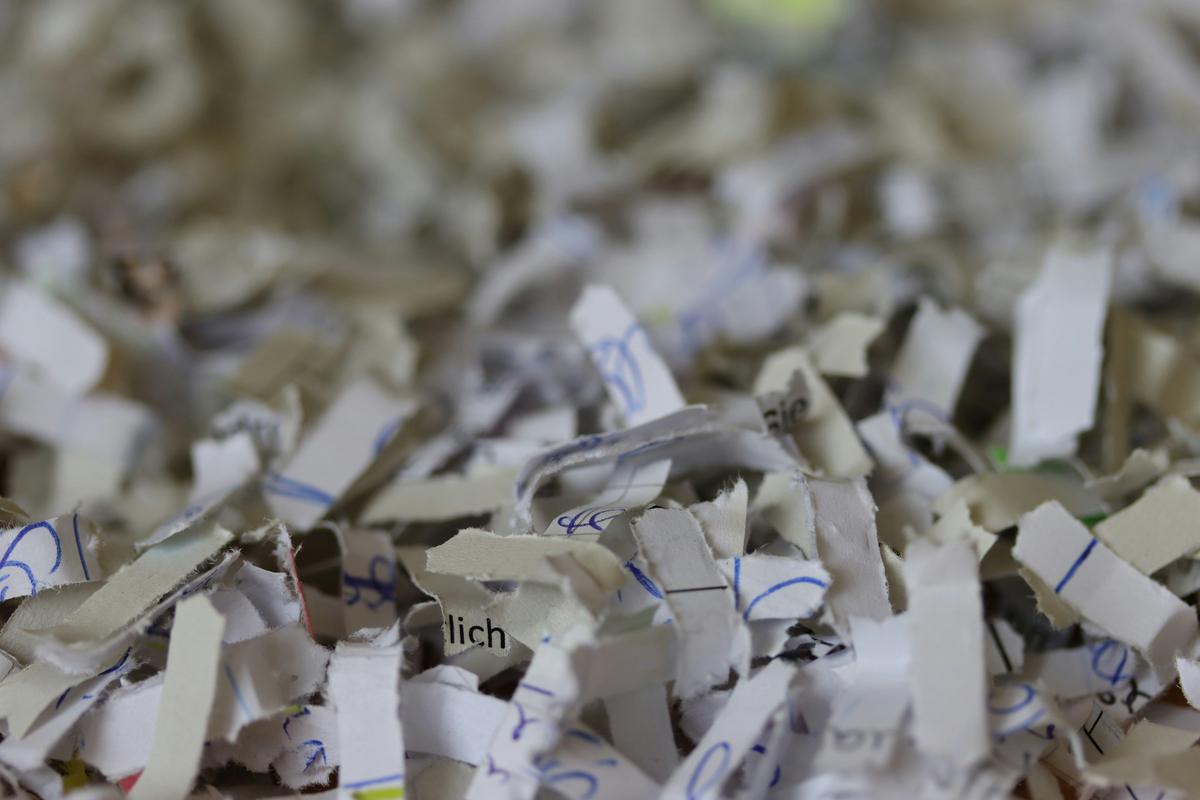 Cross-cut shredded paper strips, with handwriting reduced to unreadable fragments